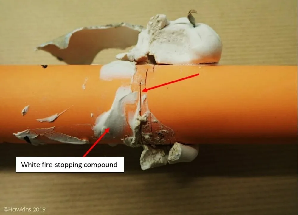 CPVC pipe failure caused by white fire-stopping compound — forensic evidence showing cracking and delamination at contact point